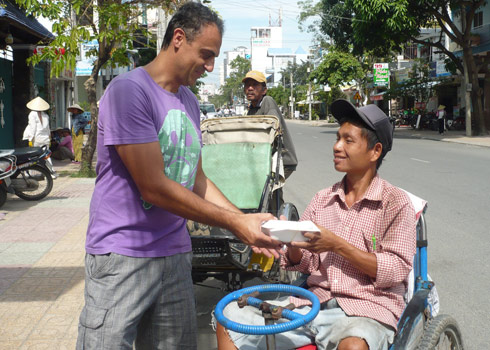 Ông chủ nhà hàng, Robert mang hộp cơm ra tận ngoài đường để cho người khuyết tật. Ảnh: Tường Châu